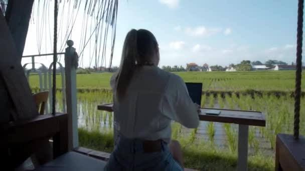 Joven Sentada Una Mesa Madera Trabajando Detrás Portátil Cafetería Tropical — Vídeos de Stock