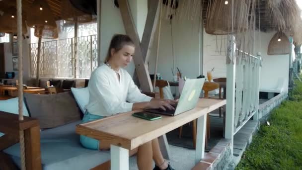 Joven Sentada Una Mesa Madera Trabajando Detrás Portátil Cafetería Tropical — Vídeos de Stock