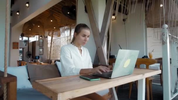 Joven Sentada Una Mesa Madera Trabajando Detrás Portátil Cafetería Tropical — Vídeos de Stock