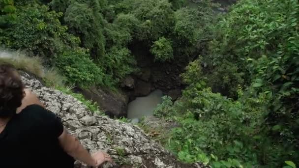 印度尼西亚巴厘岛森林中央的一个高耸的瀑布的录像 其顶部有男人 — 图库视频影像