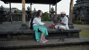 Pampatan, Rendang, Karangasem Regancy, Bali, Endonezya - 18 Temmuz 2020: Endonezyalı keşiş, Endonezyalı genç bir kadına kutsal yerde şans getirmesi için işaret etti.