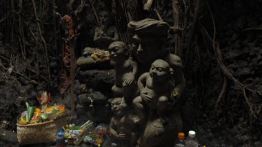 Mawar, Punggul, Kabupetan Badung, Bali, Endonezya - 28 Temmuz 2020: güçlü gölgeleri olan karanlık bir mağarada antik insan heykelleri için dini bir yer
