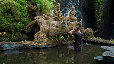 Mawar, Punggul, Kabupetan Badung, Bali, Endonezya - 28 Temmuz 2020: Endonezya 'da taştan heykeller ve şelaleli insanların yıkandığı kutsal bir yer