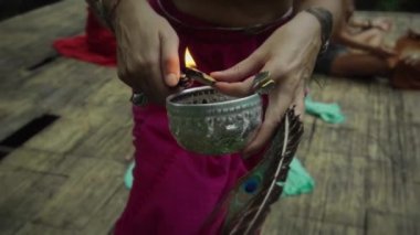 Avrupa uyruklu genç bir kızın elinde bir sandal ağacını tutarken ve onu ateşe verirken çekilmiş bir video.