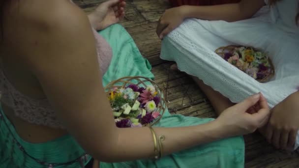 若い女の子のビデオ自然の中で花のバスケットと木製の床の上にハスのポーズに座っている — ストック動画