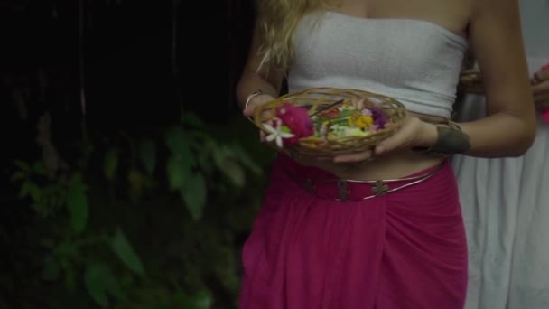 花のバスケットを保持し 熱帯雨林を歩く白い上と赤のズボンの中の若い女の子のビデオ — ストック動画