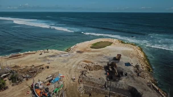 青い水で海によって砂浜の桟橋に木製のボートの建設の無人機からのビデオ — ストック動画