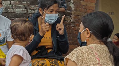 Desa Munggu, Mengwi, Kabupaten Badung, Bali, Endonezya - 26 Eylül 2020: Endonezya 'da maskeli insanlar ve çocukların olduğu küçük bir köy