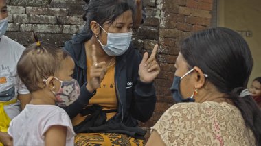 Desa Munggu, Mengwi, Kabupaten Badung, Bali, Endonezya - 26 Eylül 2020: Endonezya 'da maskeli insanlar ve çocukların olduğu küçük bir köy