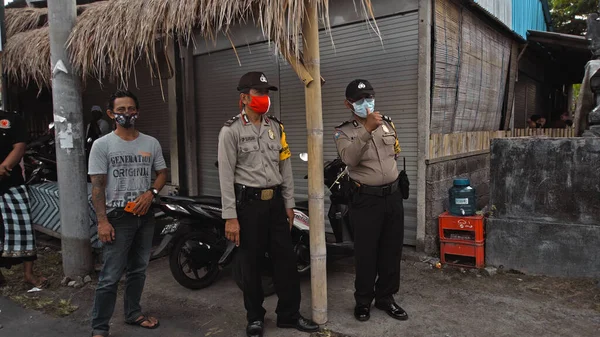 Desa Munggu, Mengwi, Kabupaten Badung, Bali, Endonezya - 26 Eylül 2020: Polis memurları sokakta tıbbi maske ve üniforma takıyor