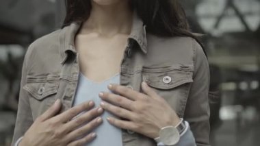Bahar kıyafetleri içinde genç bir kız elleriyle boynuna dokunuyor.