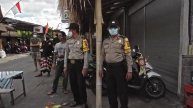Desa Munggu, Mengwi, Kabupaten Badung, Bali, Endonezya - 26 Eylül 2020: Polis memurları sokakta tıbbi maske ve üniforma takıyor