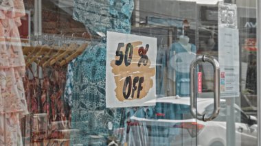 Cam bir pencereye asılı kare tabela ve% 50 indirimli.