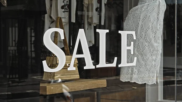 White text on the glass window of the store with the inscription sale