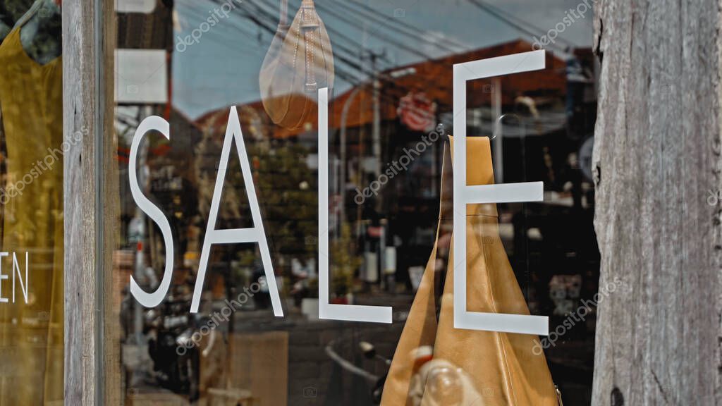 White text on the glass window of the store with the inscription sale