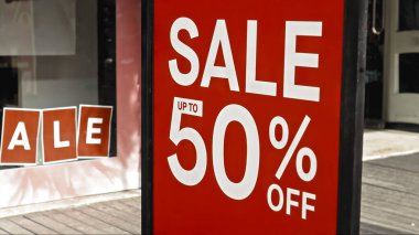 Cam bir pencereye asılı kırmızı tabela ve satışta% 50 indirim var.