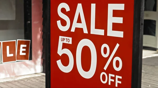 Red sign hanging on a glass window with the inscription sale up to 50% off