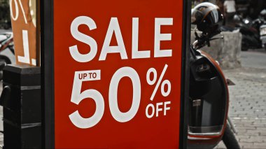 Cam bir pencereye asılı kırmızı tabela ve satışta% 50 indirim var.