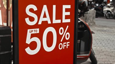 Cam bir pencereye asılı kırmızı tabela ve satışta% 50 indirim var.