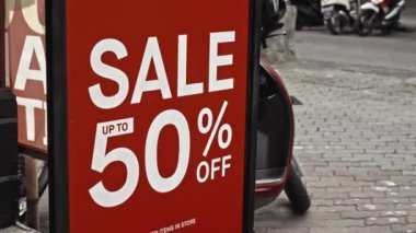 Cam bir pencereye asılı kırmızı tabela ve satışta% 50 indirim var.