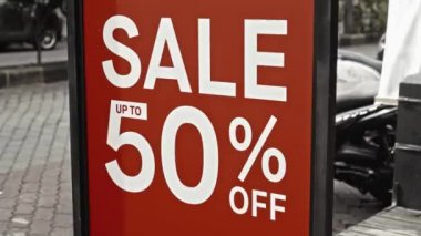 Cam bir pencereye asılı kırmızı tabela ve satışta% 50 indirim var.