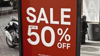 Cam bir pencereye asılı kırmızı tabela ve satışta% 50 indirim var.