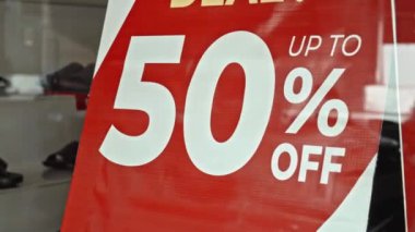 Cam bir pencereye asılı kırmızı tabela ve satışta% 50 indirim var.