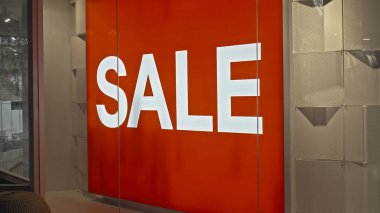 Mağazanın kırmızı pano penceresinde yazıt satışı olan beyaz metin