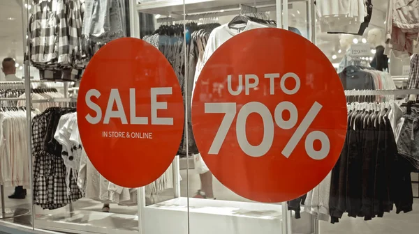 Mağazanın camındaki kırmızı etiketteki beyaz yazı% 70 'e kadar indirimli.