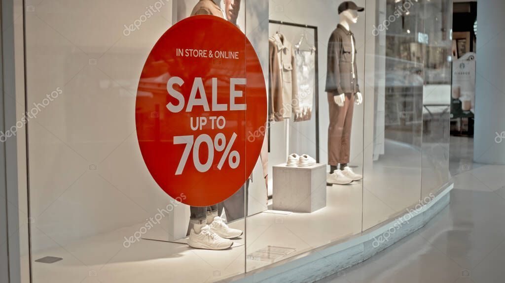 White text on the red sticker on the glass of window in the store with the inscription sale up to 70% off