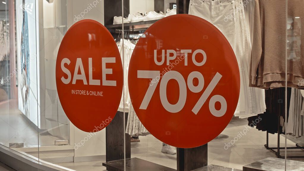 White text on the red sticker on the glass of window in the store with the inscription sale up to 70% off