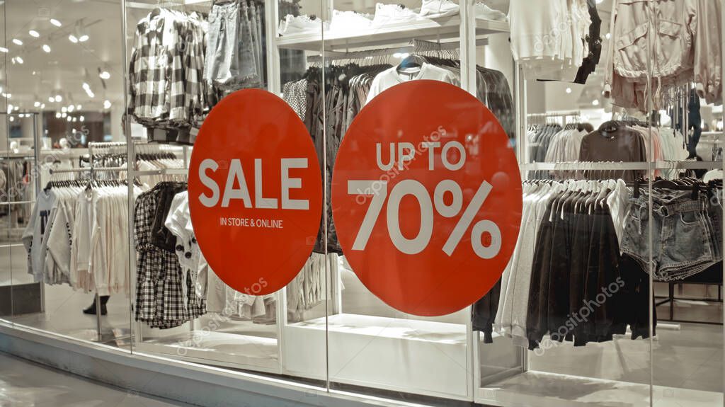 White text on the red sticker on the glass of window in the store with the inscription sale up to 70% off
