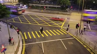 Hong Kong. İyi geceler. Kavşak yaya geçitleri ile. Canlı trafik insanlar, arabalar, otobüsler ve ünlü iki katlı tramvay. Hızlı hareket