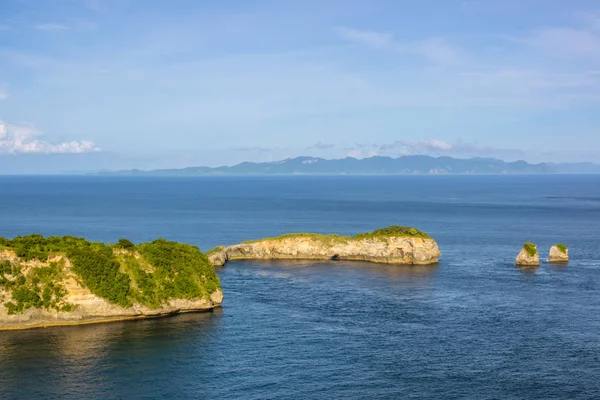 インドネシア 島の間の海峡 ジャングルと つの小さな島の岩だらけの海岸 山や地平線の雲 — ストック写真