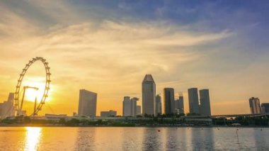 Singapur. Şehir merkezine dönme dolap ve gökdelenler ile. Günbatımı altın saat. Zaman atlamalı