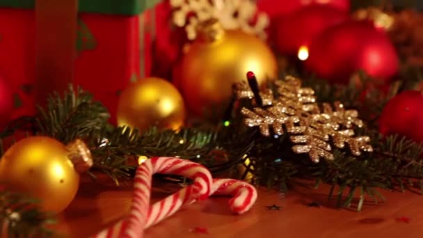 木製テーブルの上のクリスマス アイテム 枝とコーン ボール キャンドル お菓子 ギフトおよび電気のガーランドを小ぎれいにしなさい — ストック動画