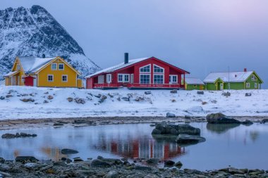 Norveç. Çok renkli evler dağlar Fiyordu kıyısında arka plan üzerinde. Kış akşam