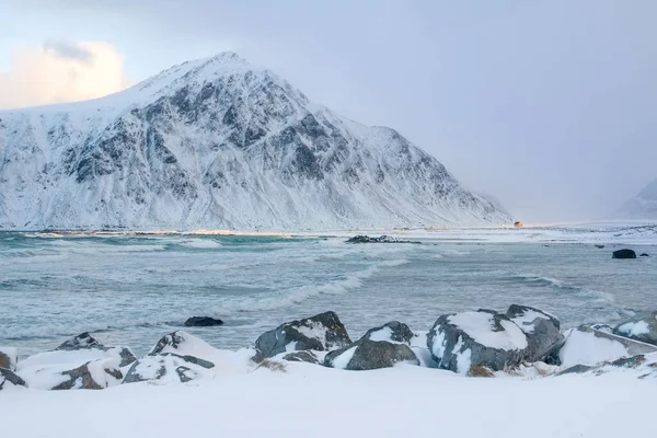 冬のノルウェー 雪をかぶった山々 に囲まれた湾 太陽の光を照らす孤独な小屋 ビーチの一部 — ストック写真