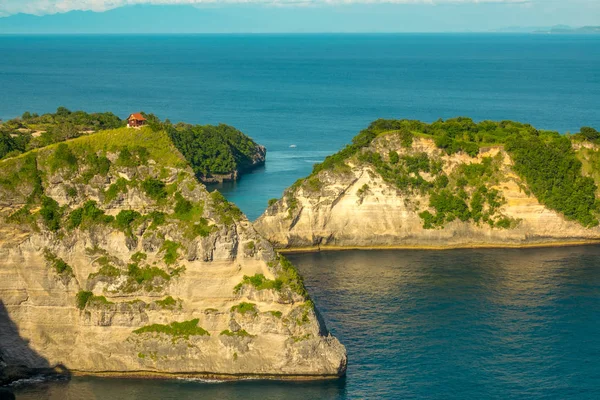 インドネシア 熱帯の島の岩だらけの海岸 山の上に小さな家 豊かな植生とターコイズ ブルーの海の水 — ストック写真