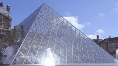 Fransa, Paris. Louvre'un avlusında güneşli bir gün. Cam piramit ve çeşmeler