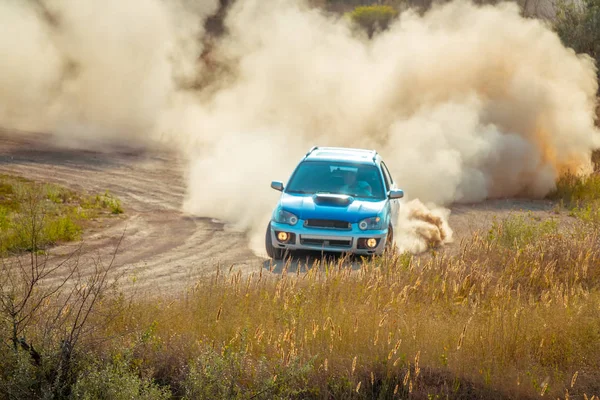 Auto sulla curva di una strada soleggiata e polverosa — Foto Stock