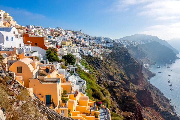 Greece. Sunny summer day over the steep coast of Santorini. Colorful buildings and yacht parking