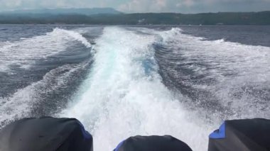 Tropik adanın yakınında güneşli bir gün. Üç güçlü motoru olan bir motorlu tekne iz bırakır. Yavaş çekim