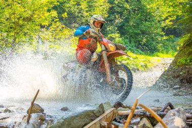 Ukrayna, Vizhnitsa - 25 Ağustos 2018: güneşli yaz günü. Bir atlet bir orman deresini geçtiğinde bir sürü su damlası dayanıklı bir motosikleti gizler. Yakın plan.