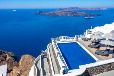 Yunanistan. Thira Adası. Santorini. Oia 'daki yüksek kıyısında bir otel. Güneşli havalarda dinlenmek için havuz ve güneş dinlenme yerleri. Deniz Burnu