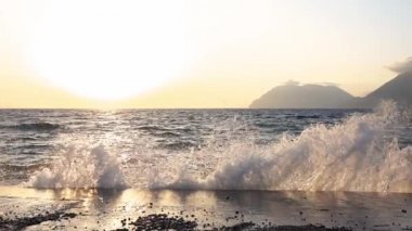 Yunanistan 'daki Rion-Antirion köprüsü yakınlarında gün batımı. Sörf dalgası beton iskeleye çarpar. Yavaş çekim