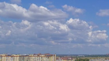 Şehrin çatılarında güneşli bir yaz günü. Mavi gökyüzünde bulutlar hızlı koşuyor. Panorama. Zaman aşımı