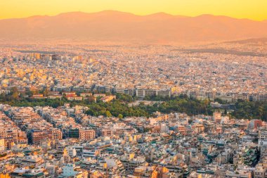 Yunanistan. Atina 'nın çatılarında sıcak bir yaz akşamı. Konut, ofis binaları ve dar sokaklar. Yeşil parklar. Hava görünümü