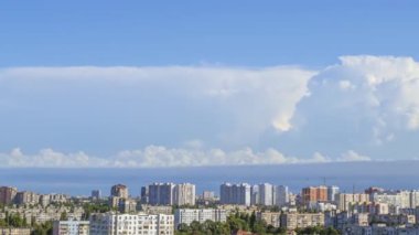 Şehrin çatılarında güneşli bir yaz günü. Mavi gökyüzünde bulutlar hızlı koşuyor. Panorama. Zaman aşımı