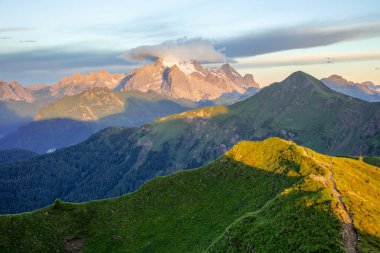 İtalyan Dolomitleri 'nde bir yaz akşamı. Batan güneşin ışınlarında yeşil ve kayalık tepeler